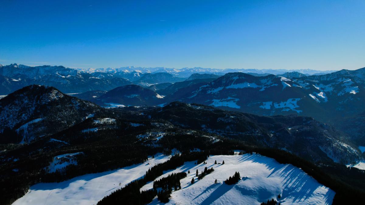Luftaufnahme der Landschaft in der Abenddämmerung, mit Bergen, die sich in die Ferne Richtung Österreich erstrecken.