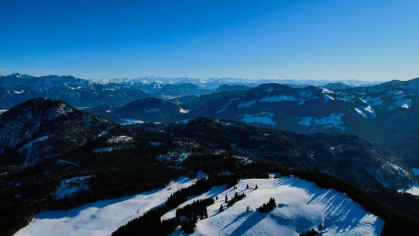 Luftaufnahme der Landschaft in der Abenddämmerung, mit Bergen, die sich in die Ferne Richtung Österreich erstrecken.