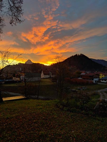 Ein Dorf, eingebettet in die Berge, erleuchtet vom warmen Schein des Sonnenuntergangs unter einem farbenfrohen Himmel.