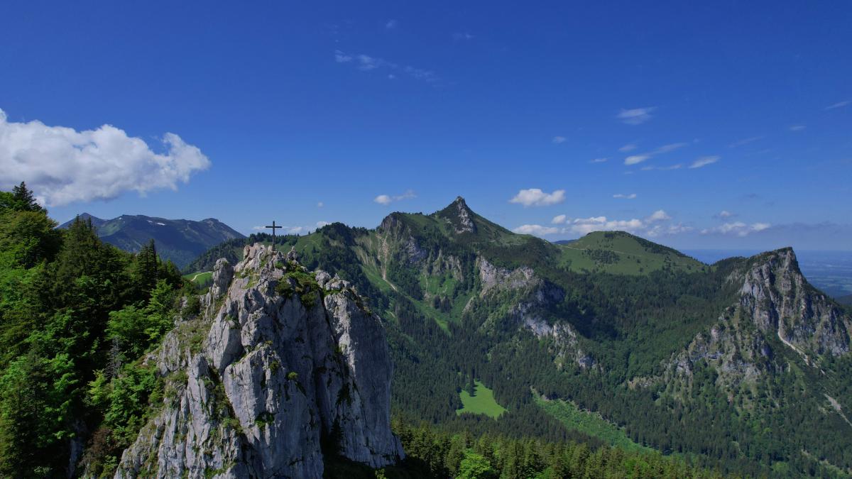 Schroffe bayerische Berglandschaft mit einem Kreuz auf felsigen Gipfeln.