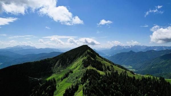 Malerischer Blick auf einen pyramidenförmigen, von Grün bedeckten Berg unter klarem Himmel.