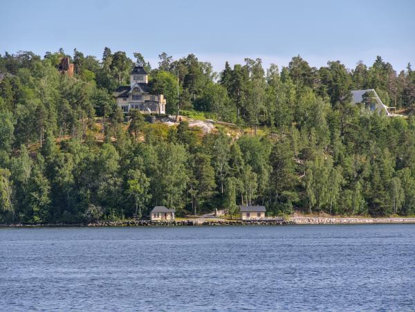Ein schwedisches Haus auf einem Hügel, darunter das Meer. Das Foto entstand im Stockholmer Schärengarten.