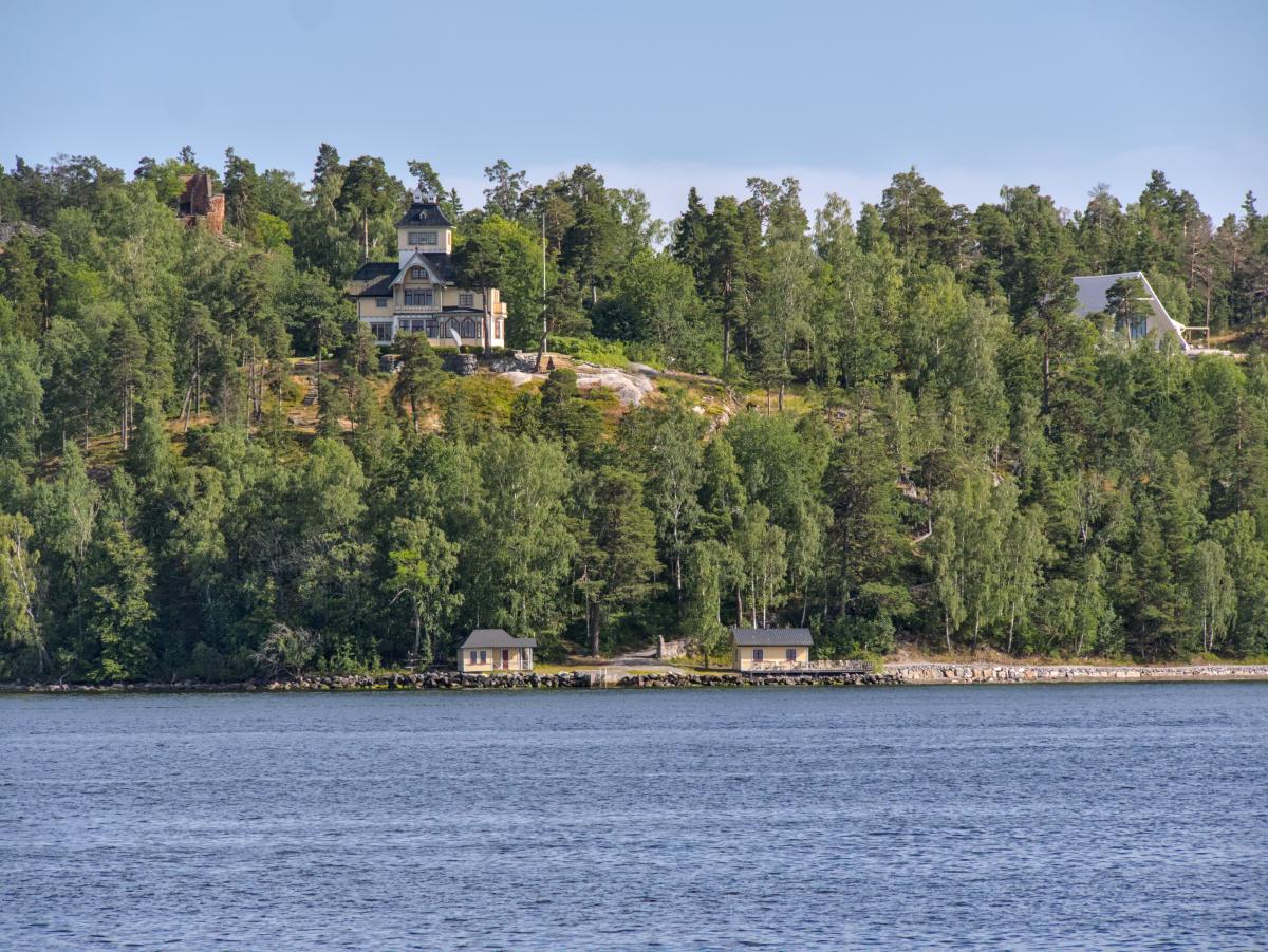 Ein schwedisches Haus auf einem Hügel, darunter das Meer. Das Foto entstand im Stockholmer Schärengarten.