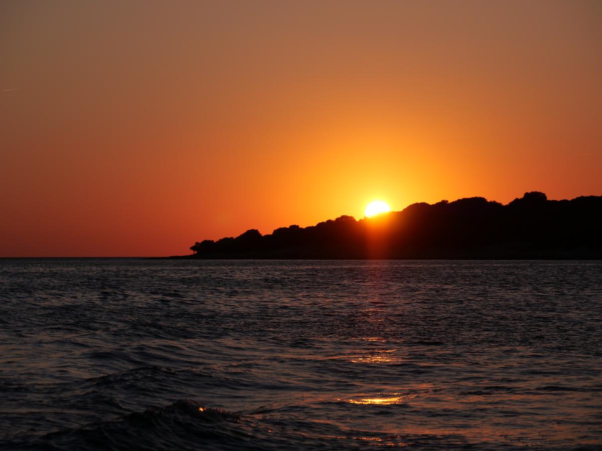 Foto des Sonnenuntergangs in Kroatien. Die Sonne geht hinter einer Insel unter.
