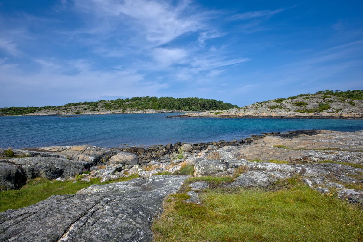Zu sehen ist die felsige schwedische Westküste mit dem Meer und einer Landformation im Hintergrund.