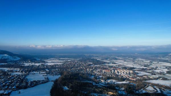 Winterblick auf ein Dorf, mit fernen Wolken, die tief über den Bergen hängen.