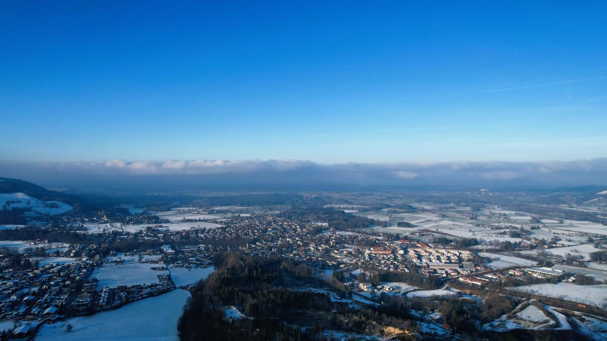 Vintervy över en by med avlägsna moln som hänger lågt över bergen.